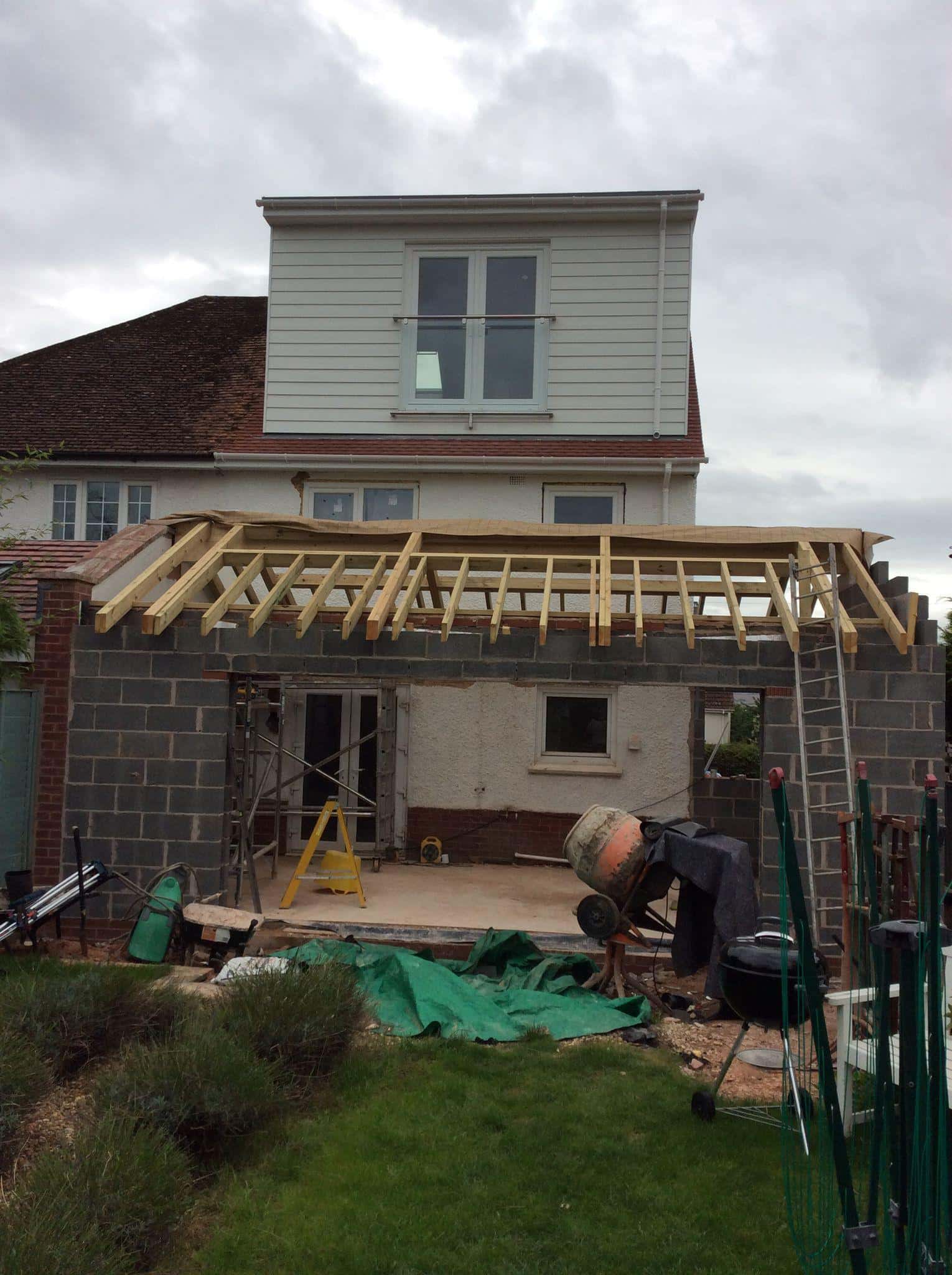 External home extension under construction with new roof framework in progress, specialising in carpentry and construction services.