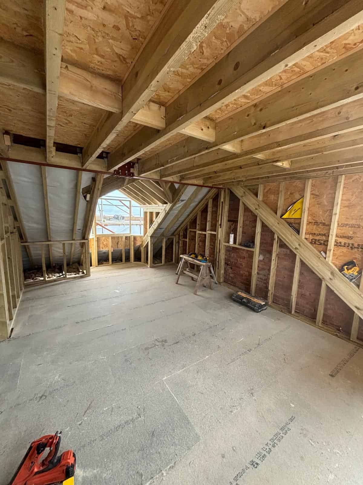 Roof space under construction with timber framing, insulated roof panels, and exposed rafters, part of JB Carpentry & Construction services.