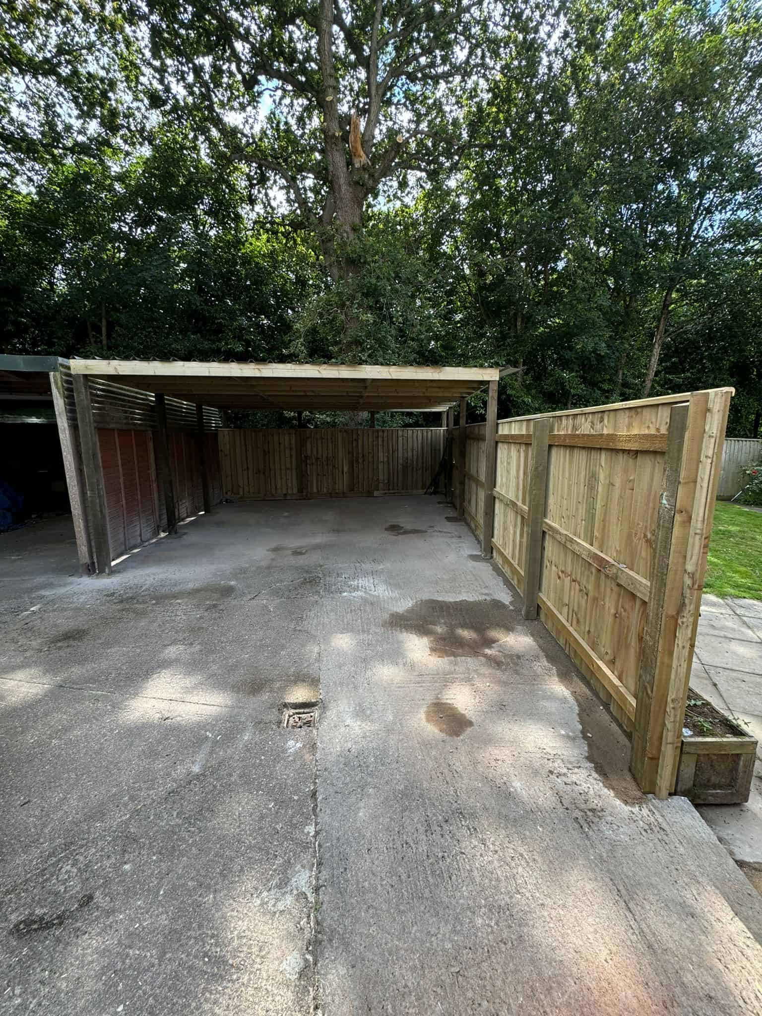 Secure wooden carport built by JB Carpentry & Construction with fencing for added privacy and protection.