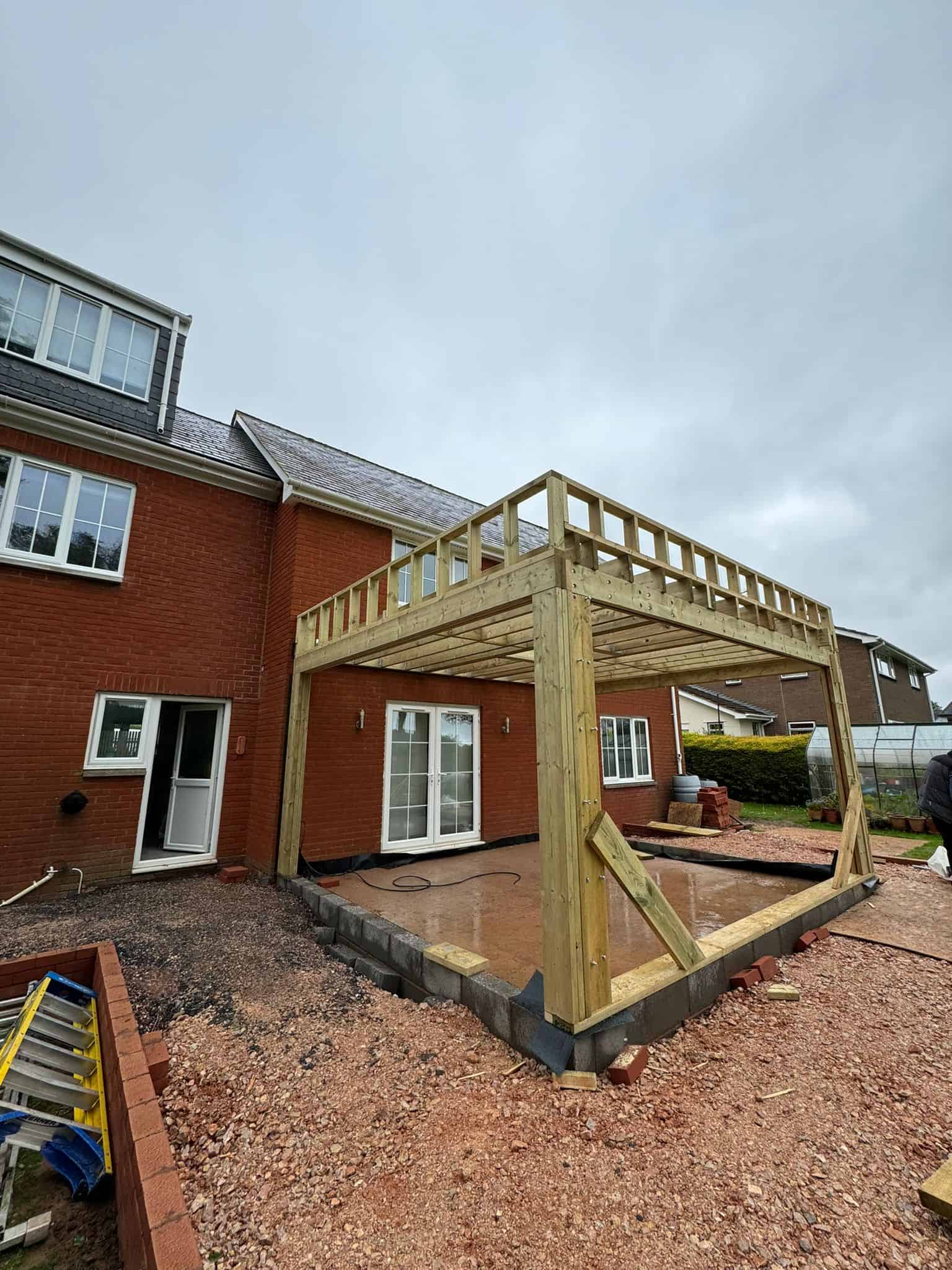 Upvc doors and windows installed on a brick house with a new wooden terrace under construction.