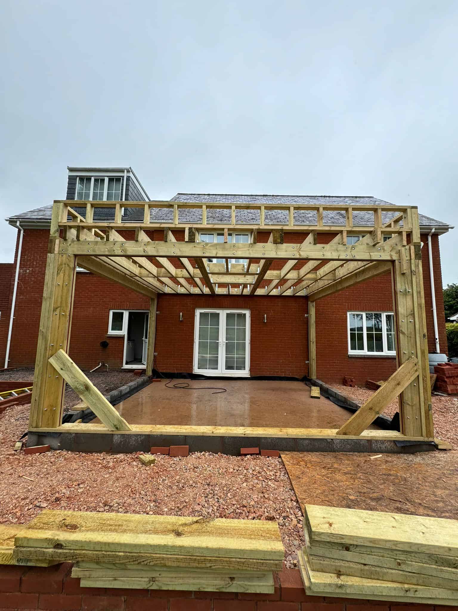New timber frame construction for outdoor decking attached to a modern brick house.