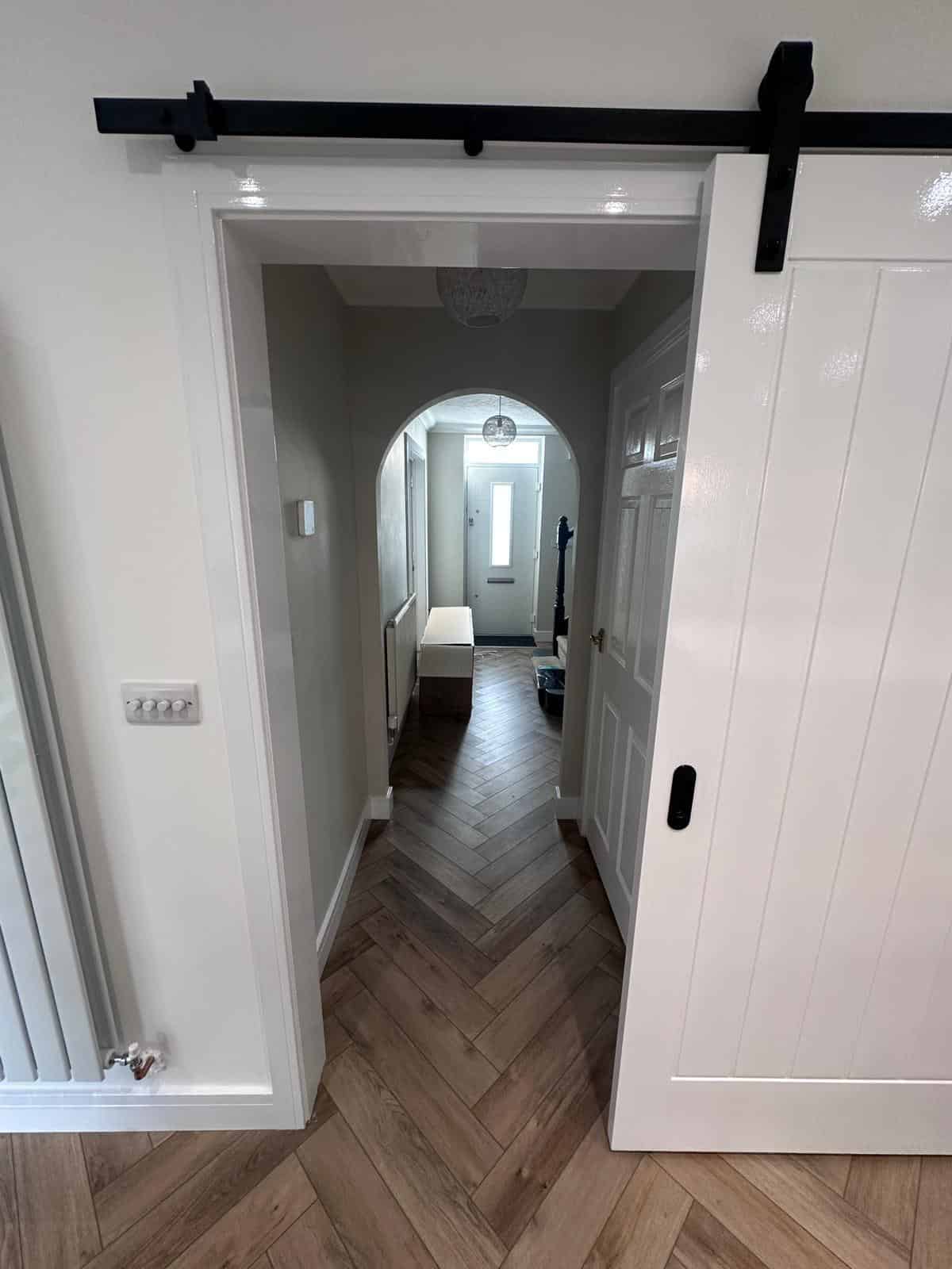 Bright and stylish interior door with sliding barn door mechanism by JB Carpentry & Construction.