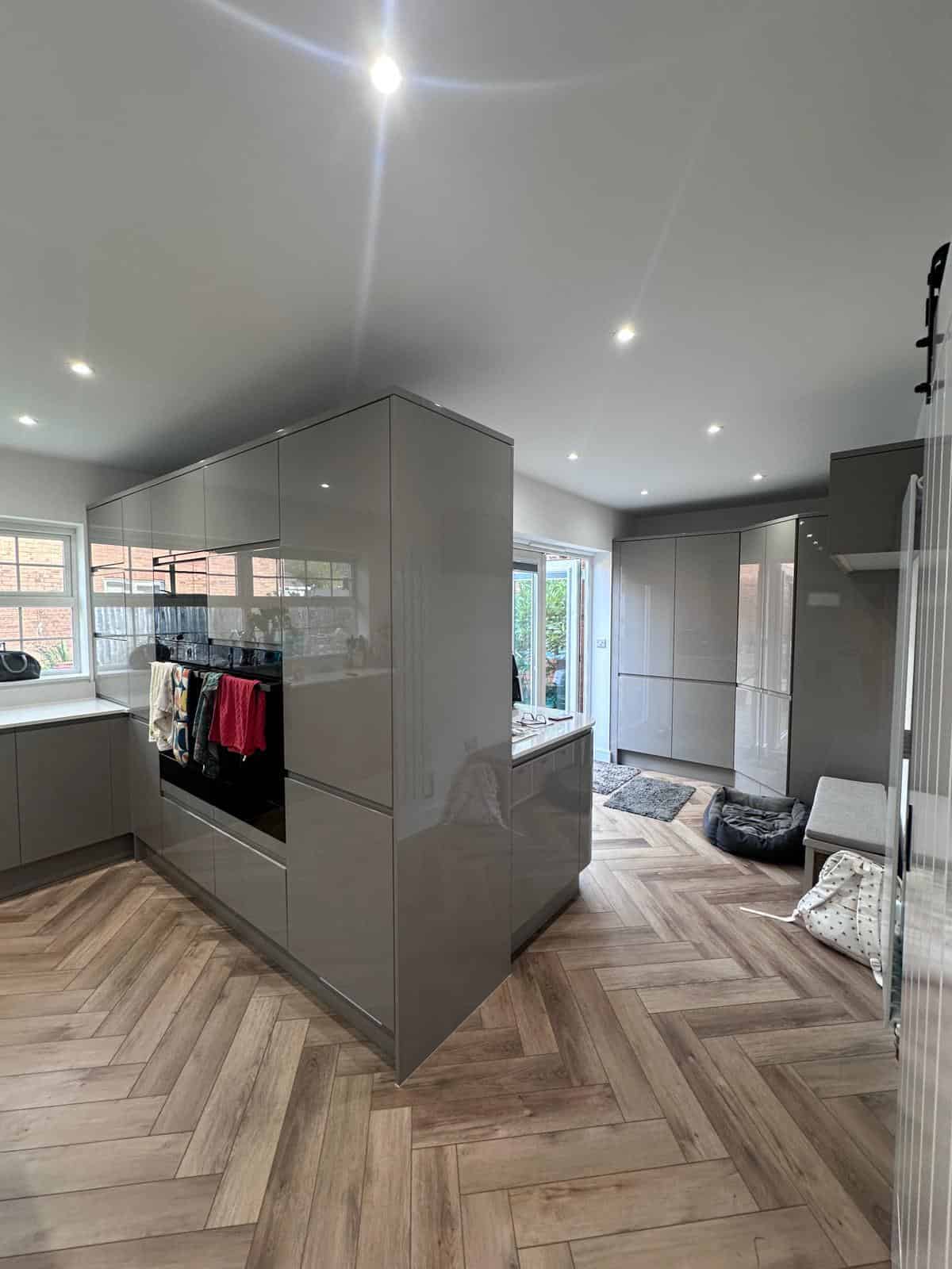 Modern grey fitted kitchen with wooden flooring and large storage units, installed by JB Carpentry & Construction.