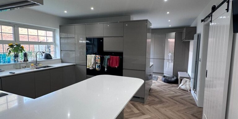 Modern kitchen with grey cabinetry and white quartz countertop, showcasing professional carpentry and construction work.